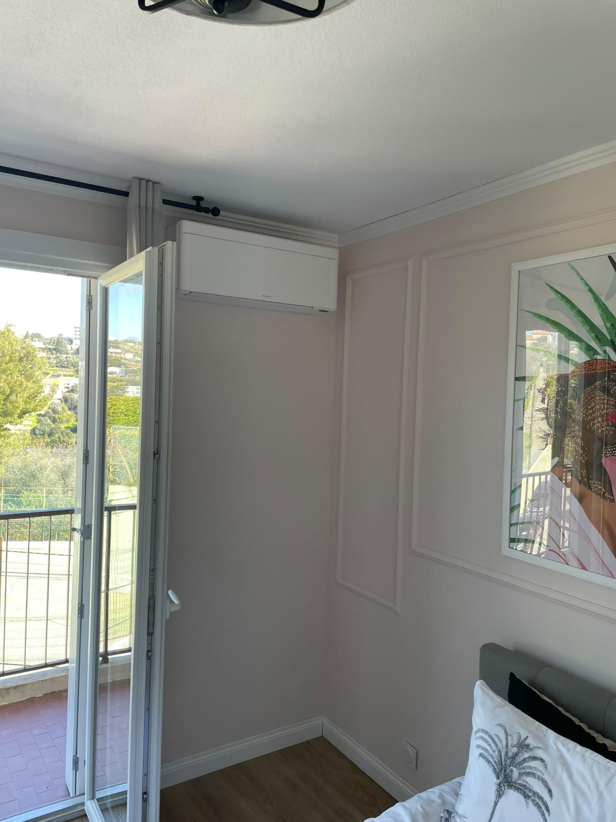 Split mural Daikin installé dans une chambre, près d’une porte-fenêtre ouverte